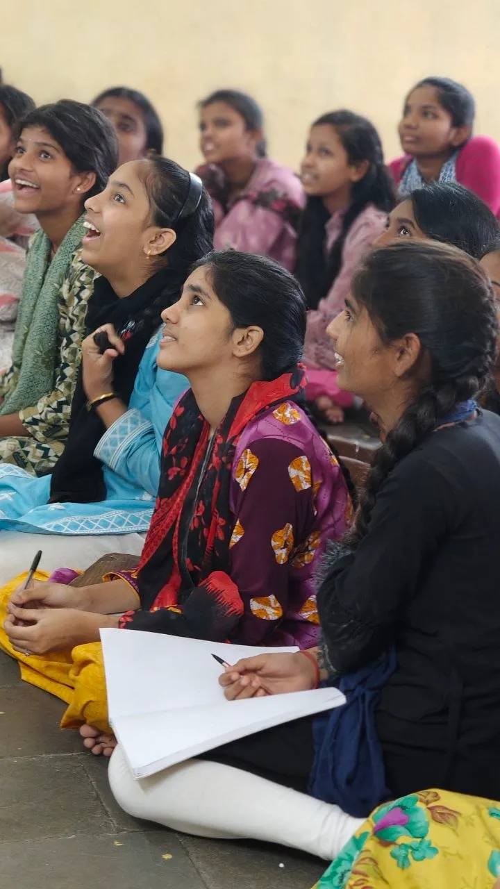 Students sitting on the floor, looking up with notebooks in hand